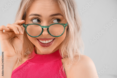 Young woman in stylish eyeglasses on light background, closeup