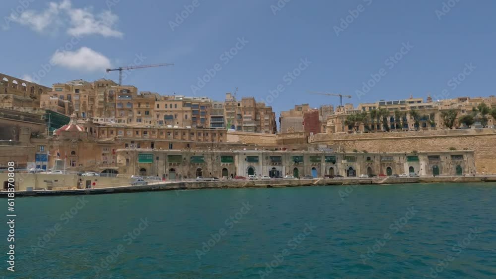View of towering cityscape port town walls of valletta malta from boat in water View of towering cityscape port town walls of valletta malta from boat in water