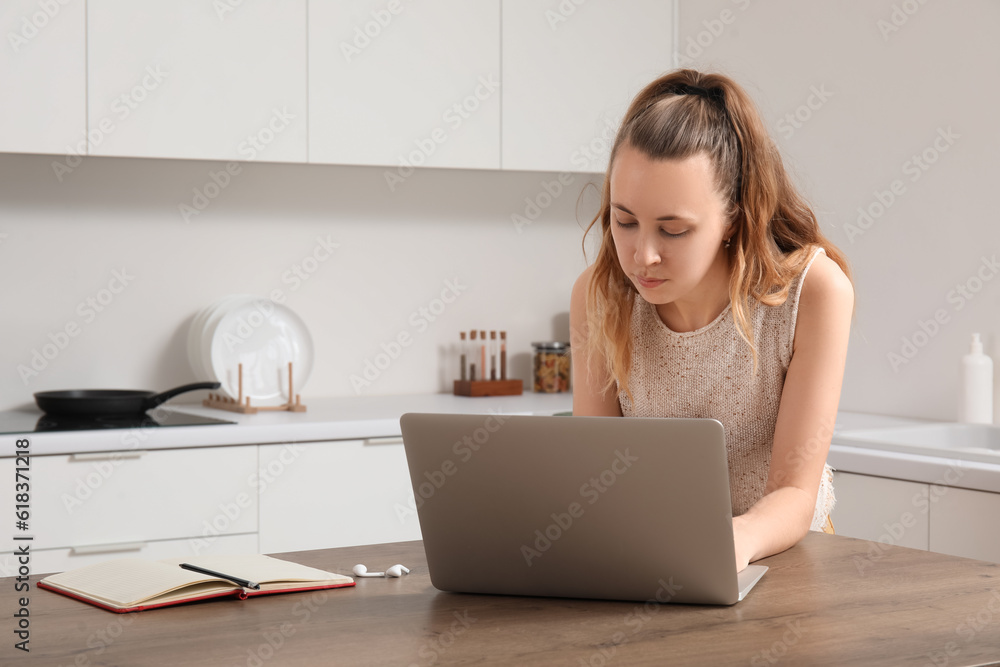 Female freelancer working with laptop at table in kitchen Female freelancer working with laptop at table in kitchen
