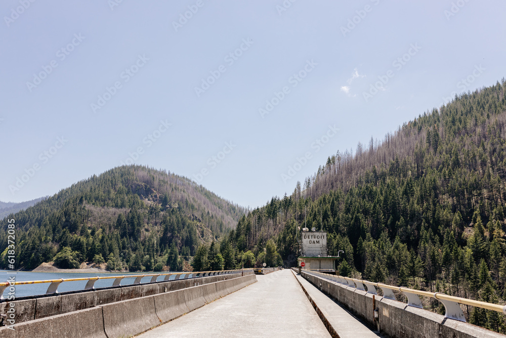 A beautiful road in the mountains among mountains, a large lake with blue water. Beautiful summer landscape with an asphalt road, mountains, trees and a river. Nature in Oregon in spring. Detroit Dam A beautiful road in the mountains among mountains, a large lake with blue water. Beautiful summer landscape with an asphalt road, mountains, trees and a river. Nature in Oregon in spring. Detroit Dam