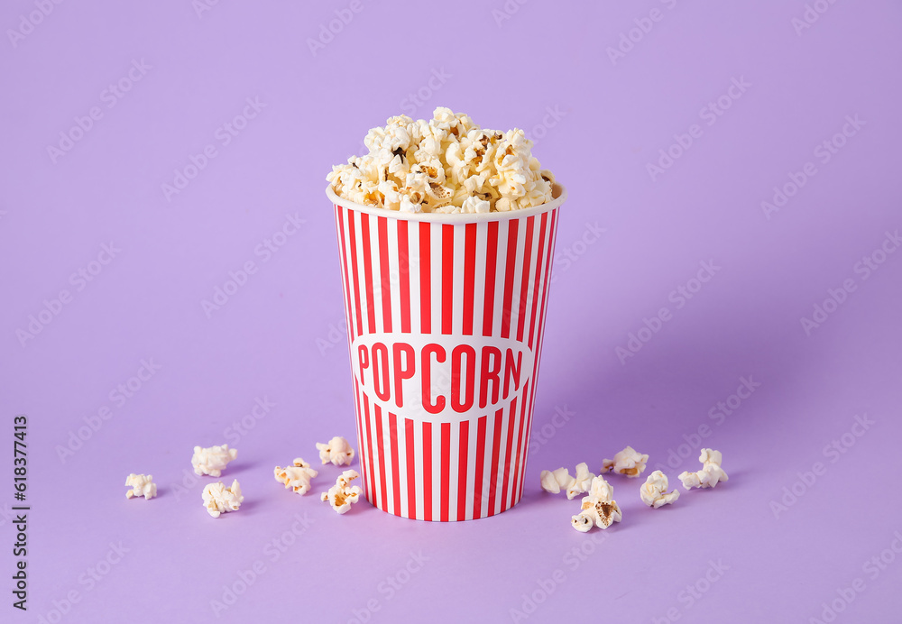 Bucket with tasty popcorn on purple background