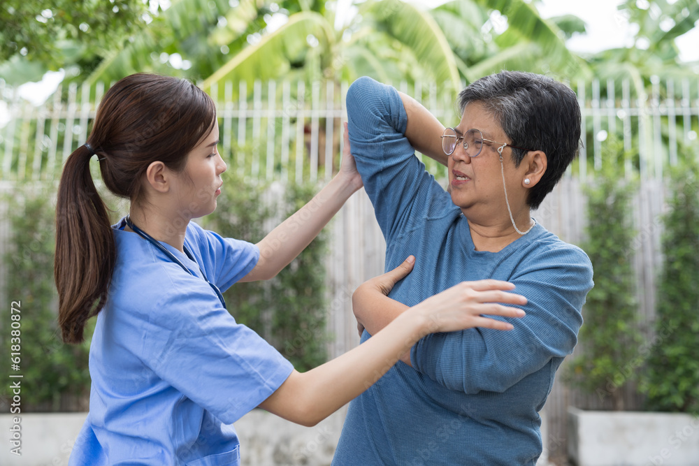 Nurse and patient elderly woman. Asian nurse taking care older woman by workout and stretch her arms in garden at home Nurse and patient elderly woman. Asian nurse taking care older woman by workout and stretch her arms in garden at home