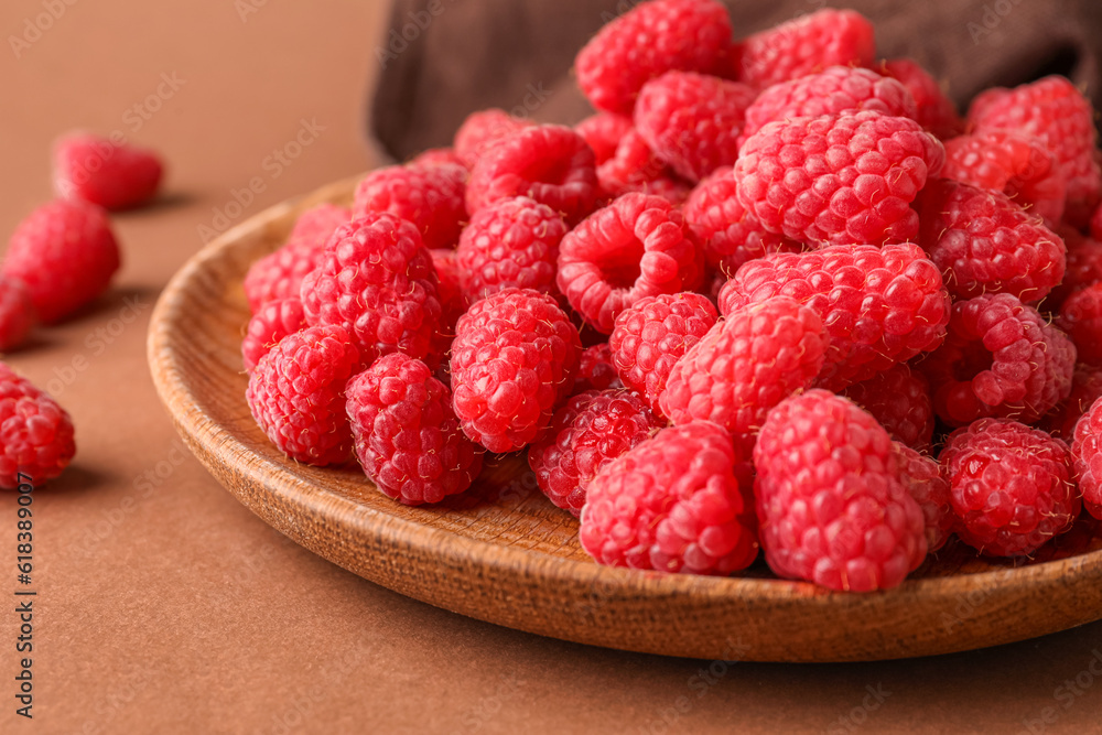 Plate with fresh raspberries on brown background Plate with fresh raspberries on brown background