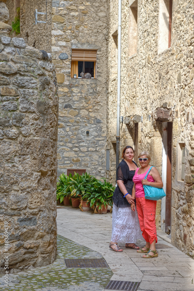 Tourist women are on narrow old street of Besalu, Catalonia.