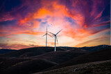 A wind farm or wind parkwith turbines at sunset clouds located in the mountains of Italy Europe and it allows to realize clean energy. It’s sustainable, renewable energy 