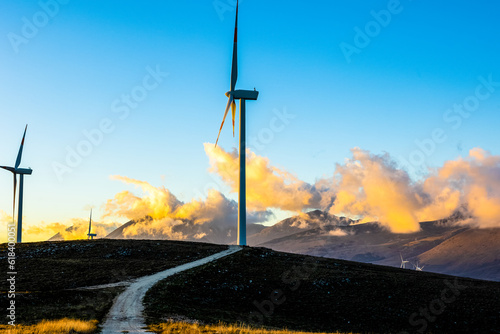 A wind farm or wind parkwith turbines at sunset clouds located in the mountains of Italy Europe and it allows to realize clean energy. It’s sustainable, renewable energy  photo