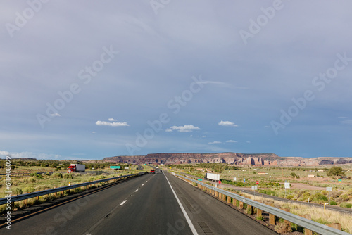 Beautiful summer landscape with highway among rocky mountains and dark blue sky with fluffy clouds on a summer day at sunset. American Roadscape with red canyons in New Mexico near Albuquerque, USA