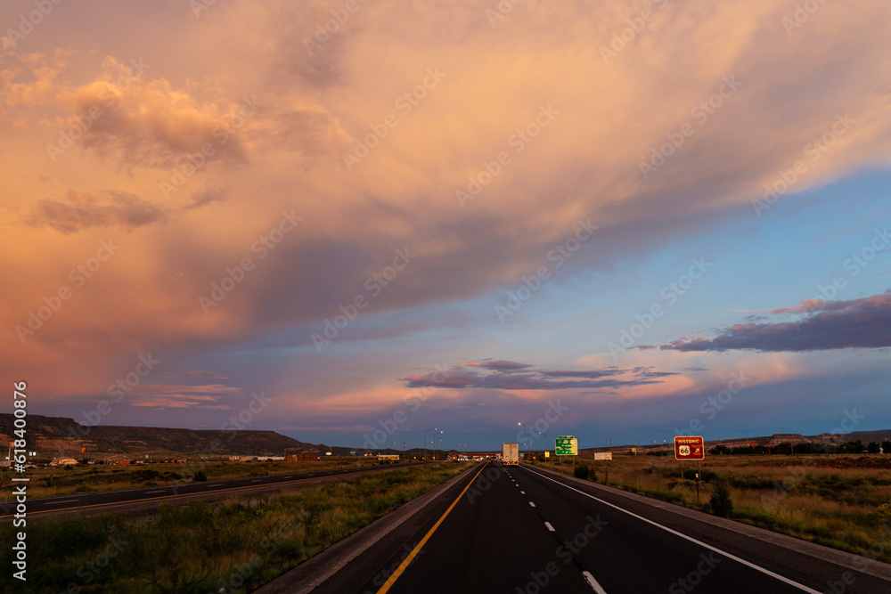 Scenic landscape with highway among mountains and colorful sky at dusk. Blue, orange and purple sky at sunset over the road. Highway 40, Arizona, USA - 06-17-2022