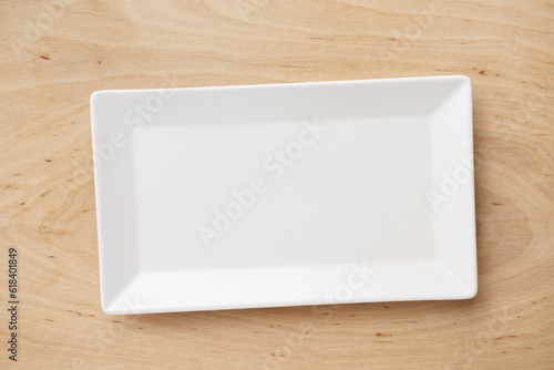 White rectangular ceramic plate on a wooden table, top view