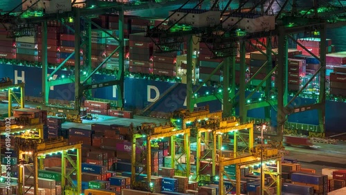 Zoom out Time lapse video of working gantry cranes at Singapore container port at night. photo