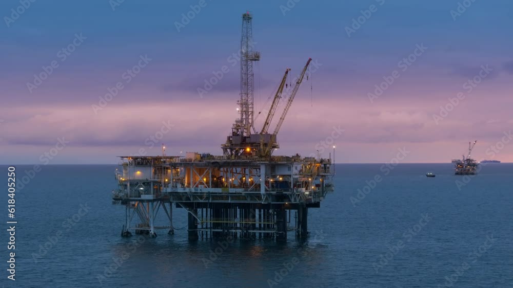 Offshore oil drilling rig for extraction of fossil fuels from the earth crust in waters of the Pacific Ocean in the evening with vessels floating behind. High quality 4k footage Offshore oil drilling rig for extraction of fossil fuels from the earth crust in waters of the Pacific Ocean in the evening with vessels floating behind. High quality 4k footage