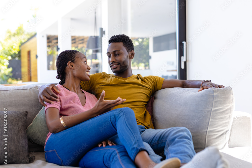 Happy african american couple smiling and embracing on couch at home