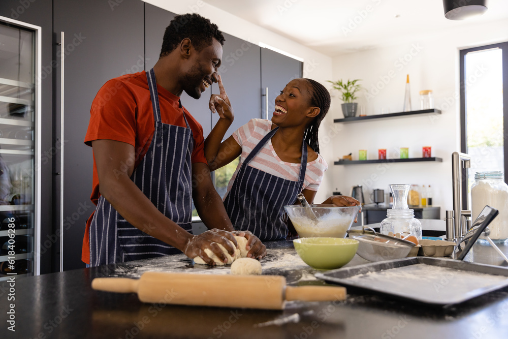 Happy african american couple in aprons preparing bread dough in kitchen Happy african american couple in aprons preparing bread dough in kitchen
