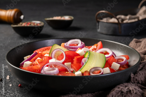 Delicious fresh salad with tomatoes, cucumber, onion and cheese on dark background. Salata de rosii cu castraveti, ceapa si branza. photo