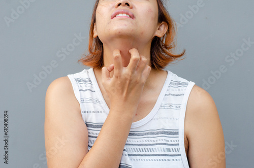 Obraz na plátně young asian woman scratching itch with hand on throat area, health care concept