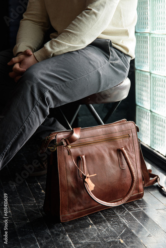 close-up photo of light brown leather briefcase on a black wooden floor.