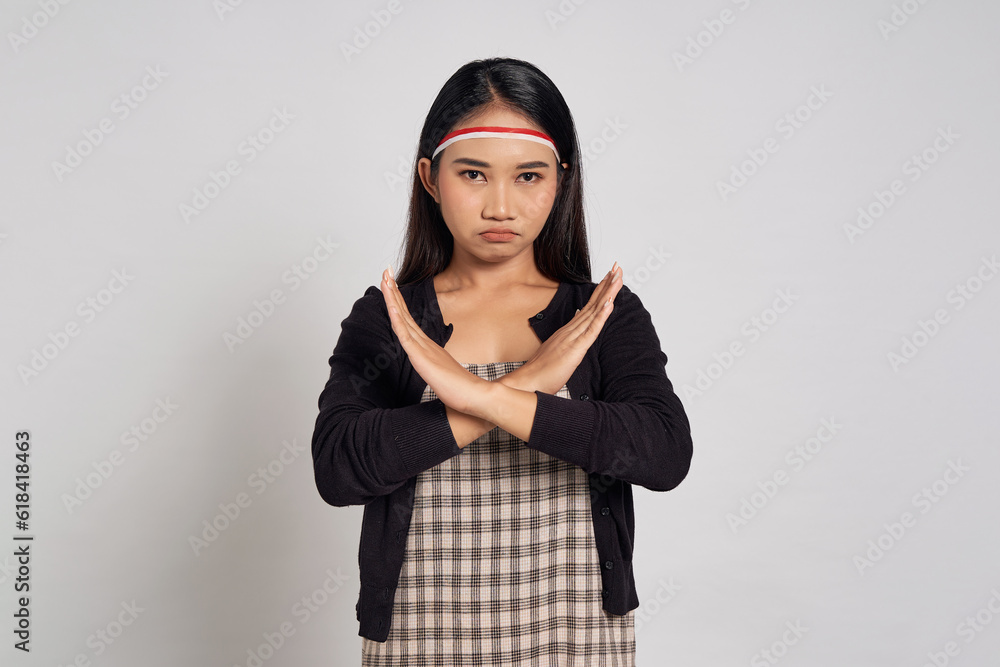 Serious Young Asian woman with crossed hands showing stop sign and prohibition sign isolated over white background. Indonesia independence day 17 August Serious Young Asian woman with crossed hands showing stop sign and prohibition sign isolated over white background. Indonesia independence day 17 August