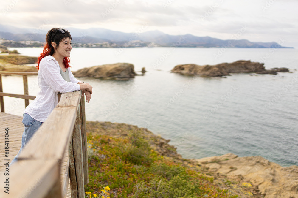 woman traveling along the coast on the rocky shore at sunset barefoot on wooden trails