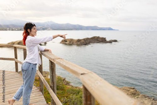 woman traveling along the coast on the rocky shore at sunset barefoot on wooden trails