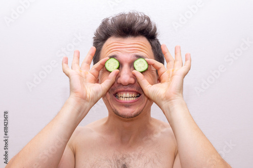 A man makes a cucumber mask: a funny concept of caring for men's health and beauty
