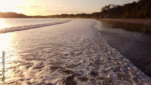 Aerial of the foamy sea hitting the Playa Carrillo beach during the bright sunset in Costa Rica photo