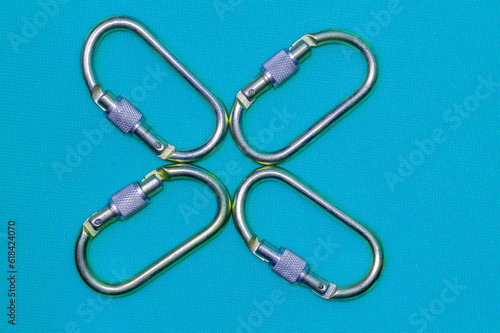 A flower from steel climbing four carabiners on a light blue background