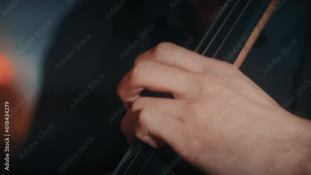 Closeup video of a cellist playing strings with fingers on a dark background Closeup video of a cellist playing strings with fingers on a dark background