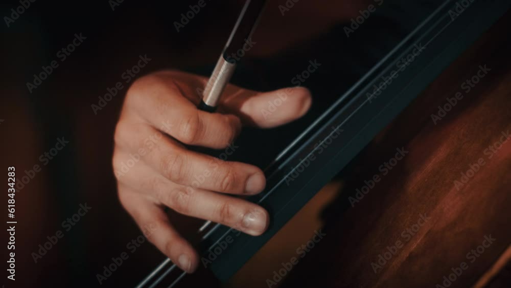 Closeup video of a cellist playing strings with fingers on a dark background Closeup video of a cellist playing strings with fingers on a dark background