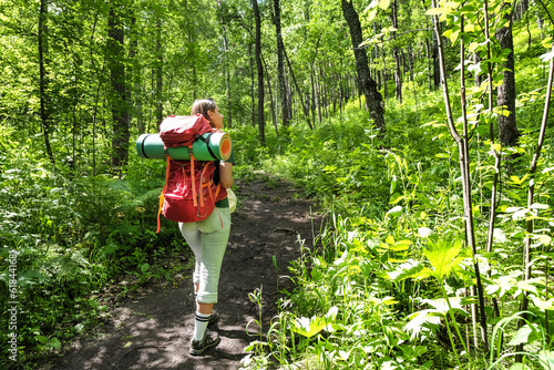 Young female tourist with backpack walking in forest