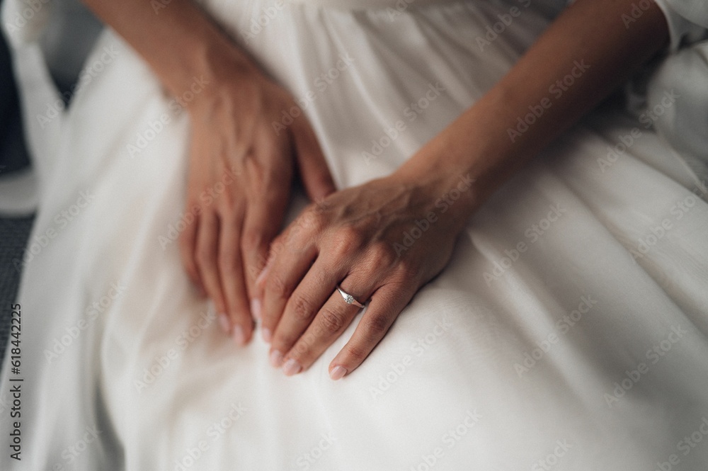 Closeup shot of the bride's hands on her white dress. Closeup shot of the bride's hands on her white dress.