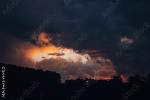 Beautiful scene of a cloudy sunset sky over the silhouette of trees.
