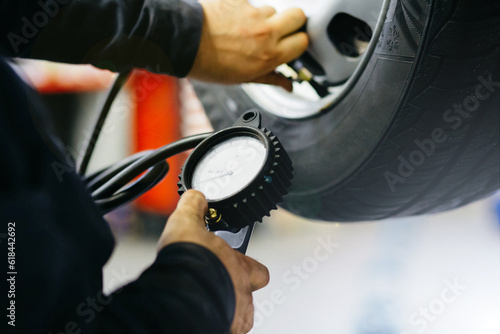 Close up mechanic inflating tire and checking air pressure with gauge pressure in service station photo
