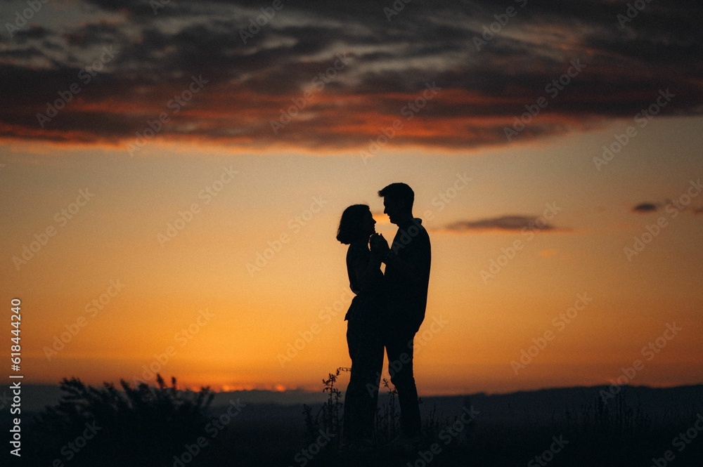 Happy young couple posing in a sun-drenched meadow at sunset.