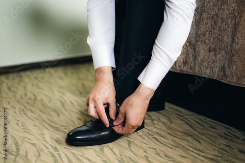 Closeup shot of a groom adjusting his shoelace.