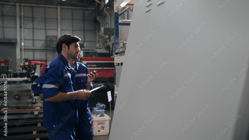 Two professional manager worker men in uniform safety checking quality of steel part in production line in steel factory Two professional manager worker men in uniform safety checking quality of steel part in production line in steel factory