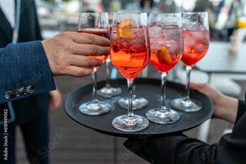Man taking a glass of Aperol from a silver tray with glasses of beverage