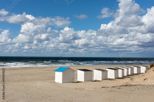 Stunning scene of beach huts lined up against the backdrop of rolling sand dunes on the coastline