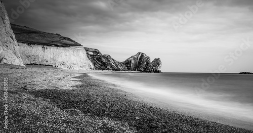 Stunning black and white shot of a beach located at the edge of a dramatic cliffside in England
