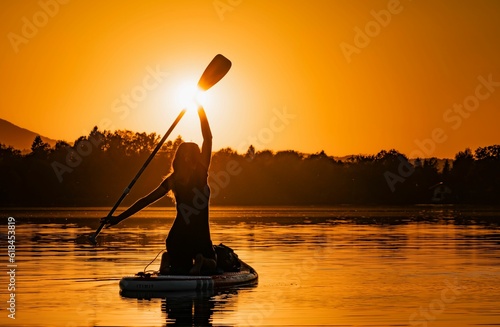 Beautiful silhouette of a woman in a canoe against the backdrop of a stunning sunset photo