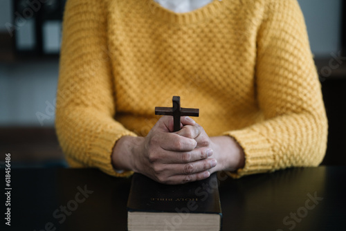 Closeup of simple wooden Christian cross on Bible. Concept of hope, faith, christianity, religion.