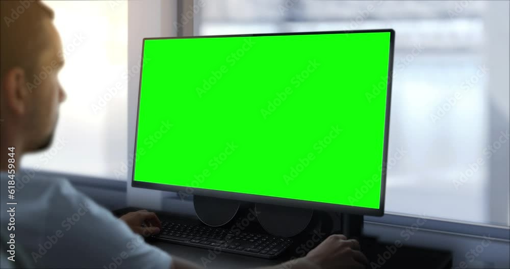 An engineer works on a computer with a green screen. In the background, there is a production hall, a template for work in a design facility in the technological, mechanical, or IT industry An engineer works on a computer with a green screen. In the background, there is a production hall, a template for work in a design facility in the technological, mechanical, or IT industry