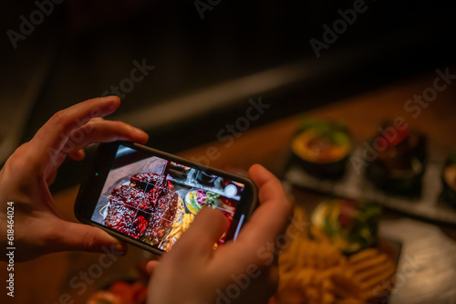 hand with smartphone photographing food at restaurant or cafe