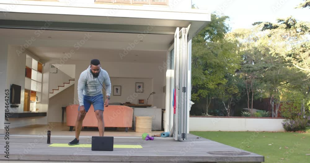 Focused african american man fitness training stretching on deck in sunny garden, slow motion Focused african american man fitness training stretching on deck in sunny garden, slow motion