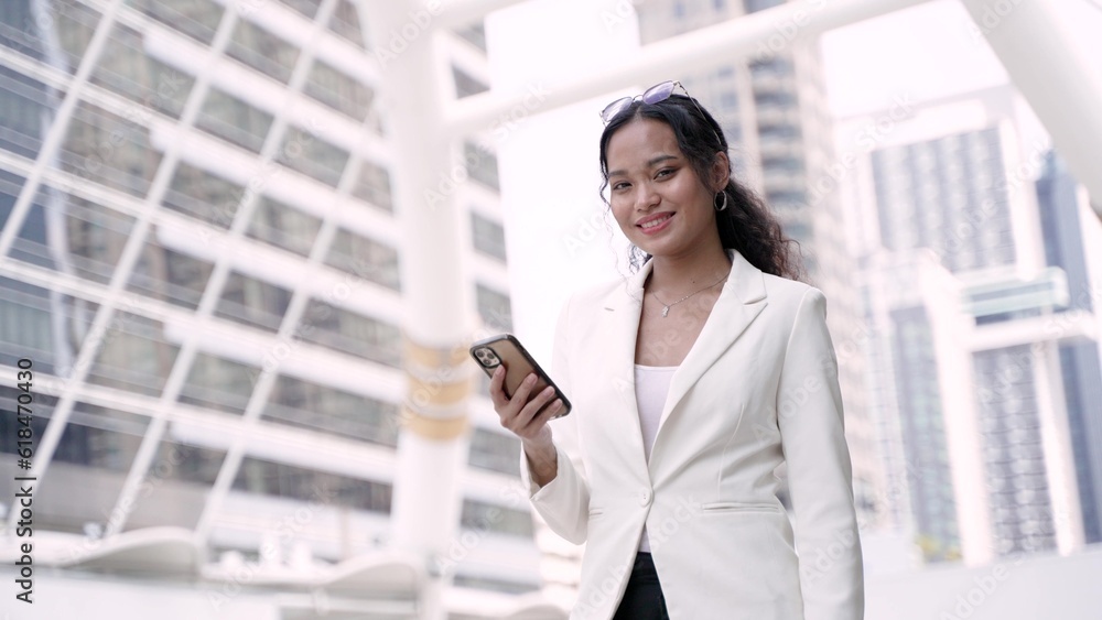 Asian executive working woman holding and using mobile phone in the street