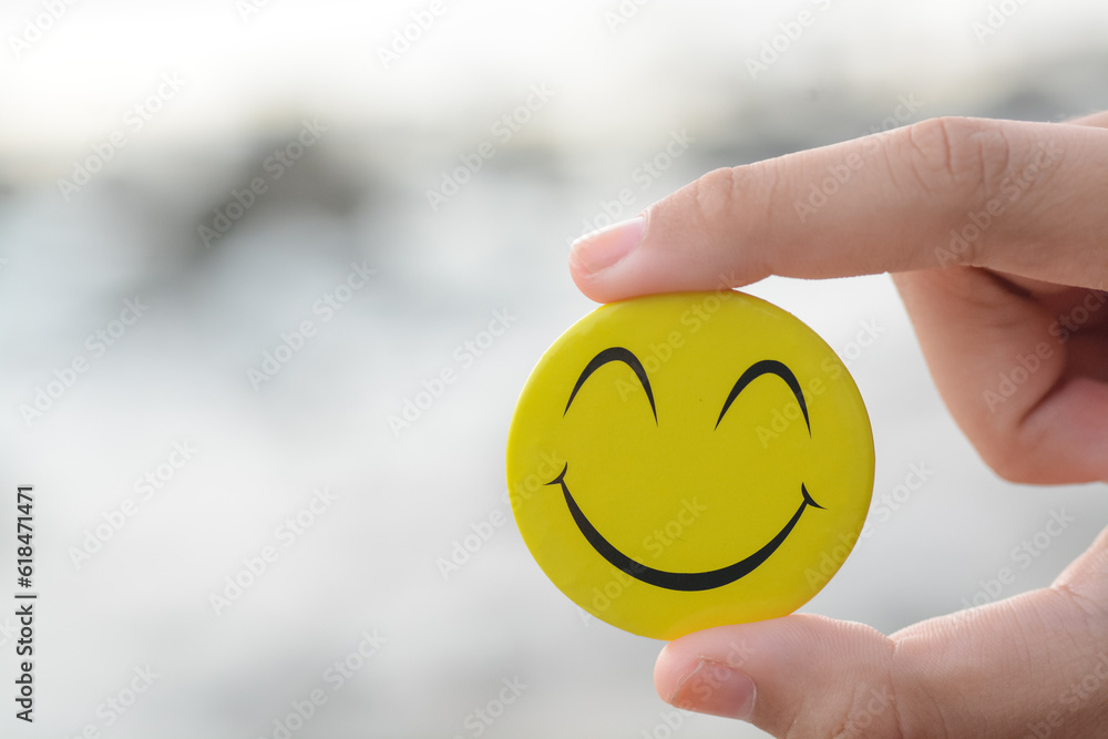 A hand holding a smiling face symbolizes a positive mindset, constructive feedback, a joyful approach to life, and a commitment to a healthy lifestyle. A hand holding a smiling face symbolizes a positive mindset, constructive feedback, a joyful approach to life, and a commitment to a healthy lifestyle.