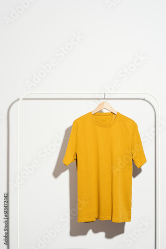 Yellow t-shirt on wooden hanger displayed on a clothes rack