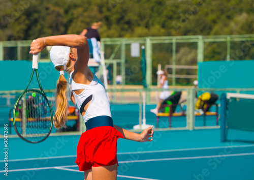A girl plays tennis on a court on a summer sunny day