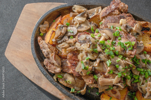 Baked chicken livers and potatoes with garlic, herbs, and fried onion in a cast iron skillet