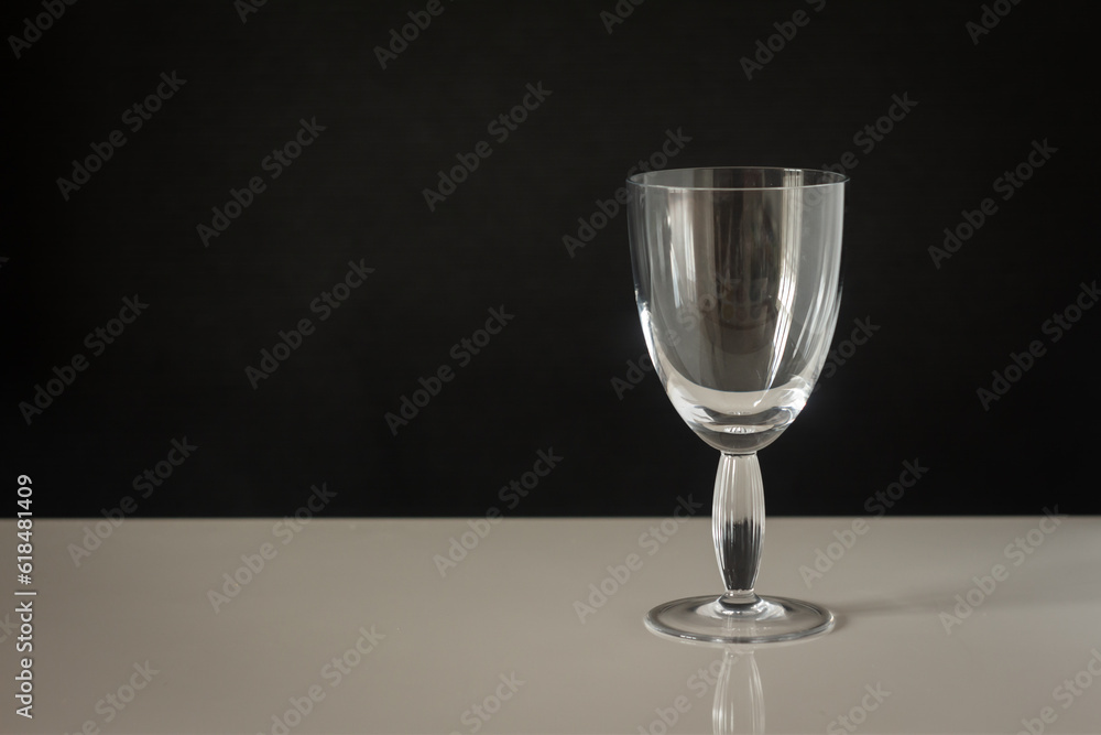 a large glass with a thick stem on a dark background and a white table a large glass with a thick stem on a dark background and a white table