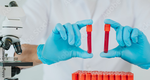 фотографія Close up of male doctor taking blood sample tube from rack with analyzer in lab